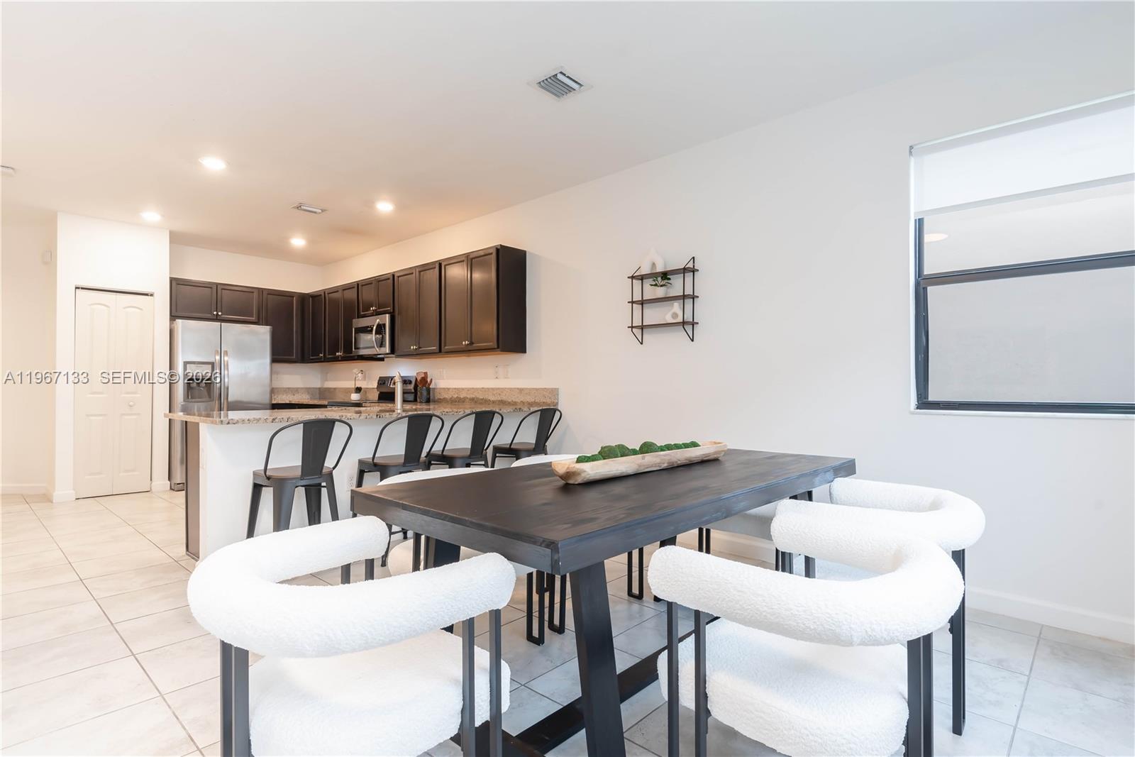 25128 Southwest 113th Place Homestead, FL 33032 - Photo 17 of 39 a kitchen with stainless steel appliances kitchen island granite countertop a dining table and chairs
