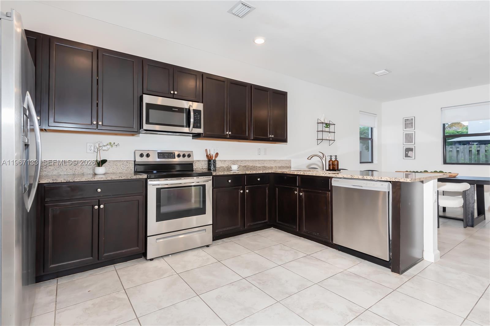 25128 Southwest 113th Place Homestead, FL 33032 - Photo 6 of 39 a kitchen with stainless steel appliances granite countertop a stove top oven a sink dishwasher and a refrigerator
