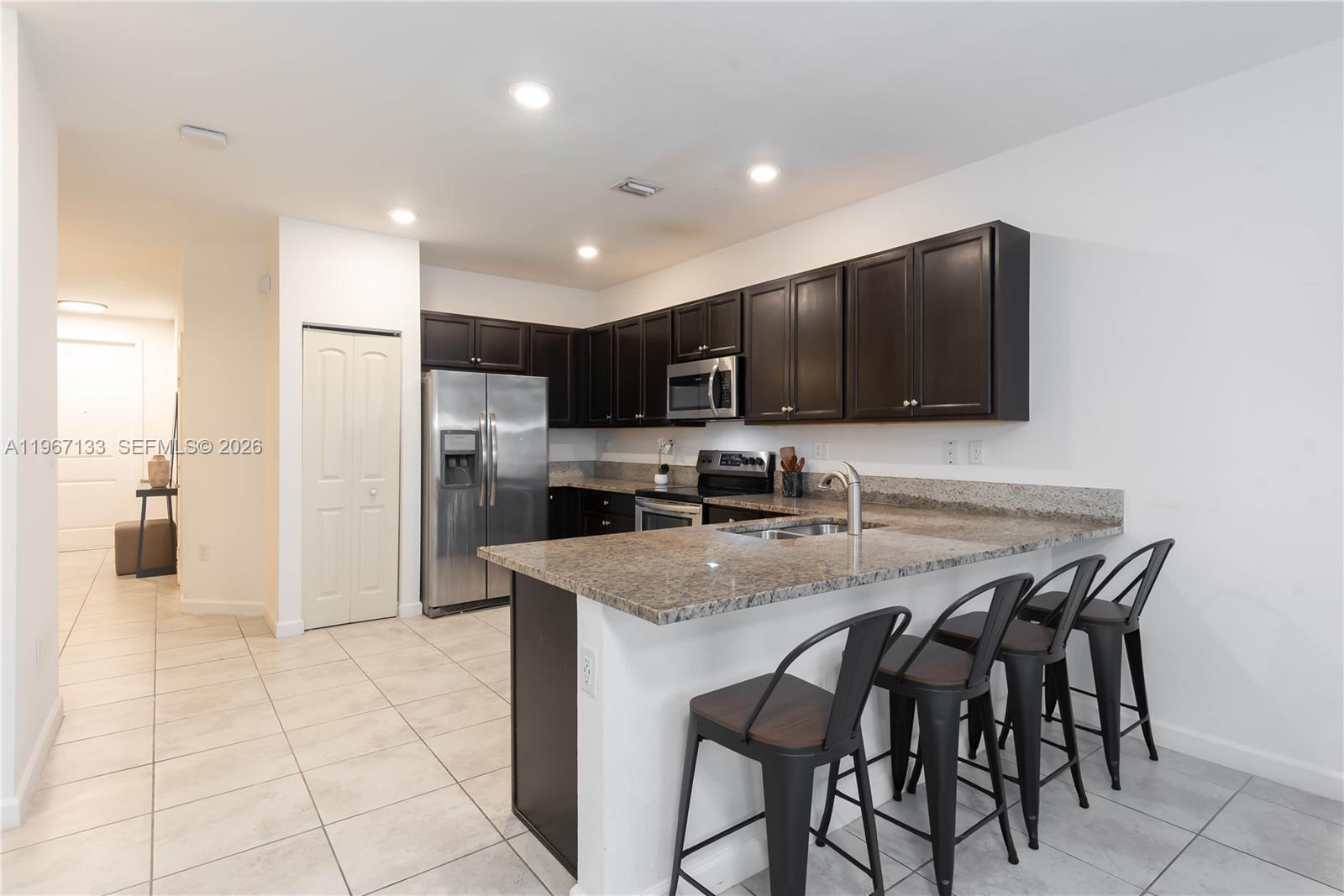 25128 Southwest 113th Place Homestead, FL 33032 - Photo 7 of 39 a kitchen with stainless steel appliances granite countertop a stove a sink a microwave a refrigerator and cabinets