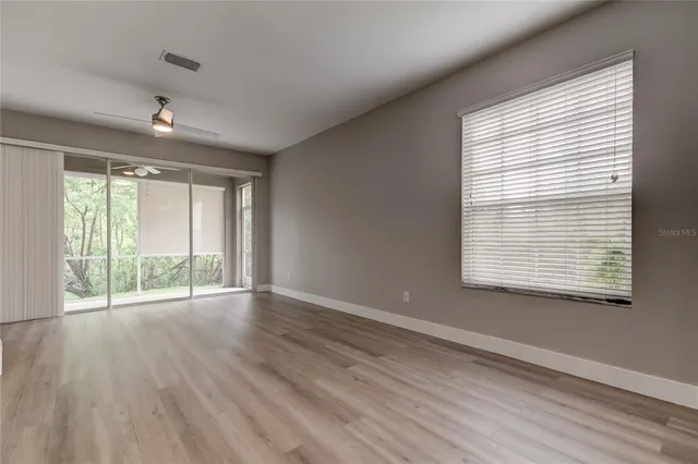 a view of an empty room with wooden floor and a window