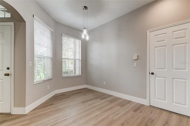 an empty room with wooden floor cabinet and windows