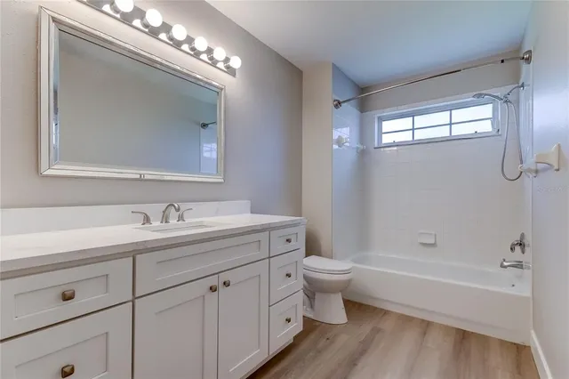 a bathroom with a toilet a sink a mirror a bathtub and vanity