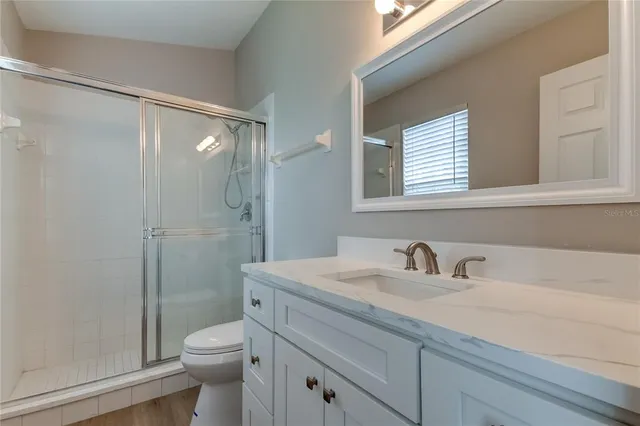 a bathroom with a sink a mirror a toilet and shower