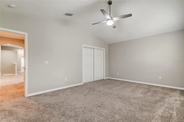 an empty room with closet and ceiling fan