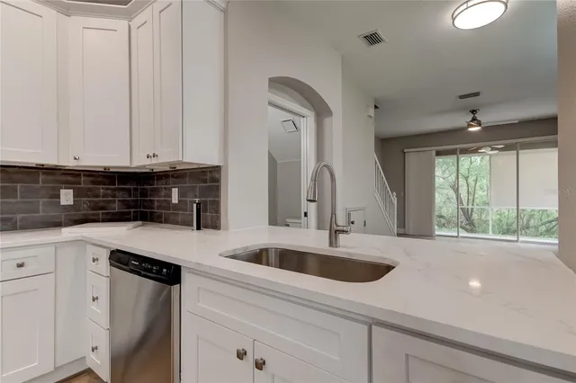 a kitchen with stainless steel appliances granite countertop a sink a washer and dryer with wooden cabinets