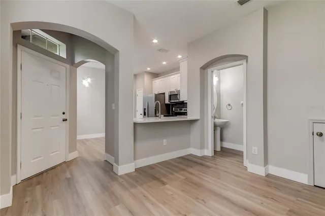 a view of a hallway with wooden floor and a kitchen