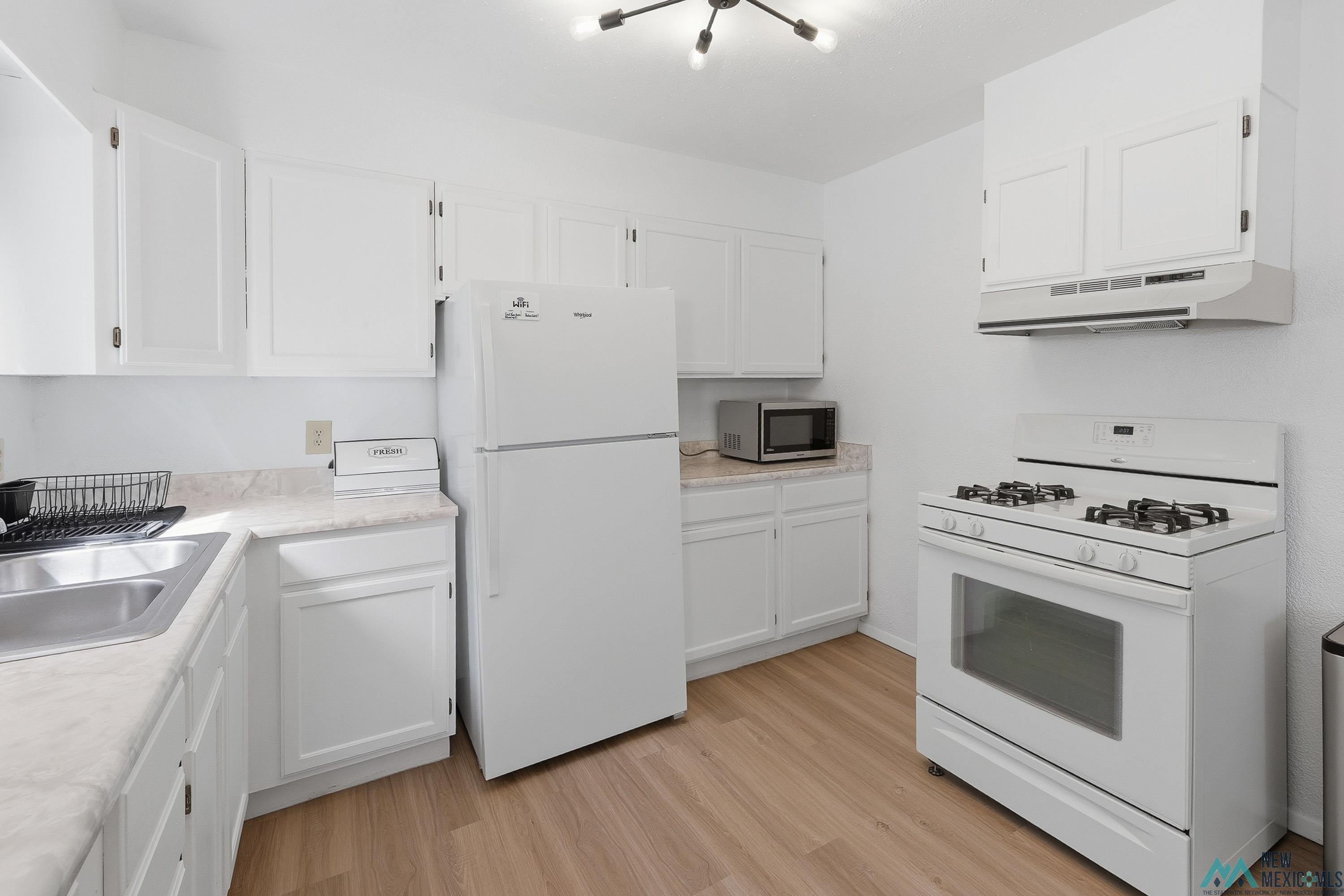 120 South 5th Street Raton, NM 87740 - Photo 9 of 25 Kitchen featuring white appliances, light countertops, and white cabinets