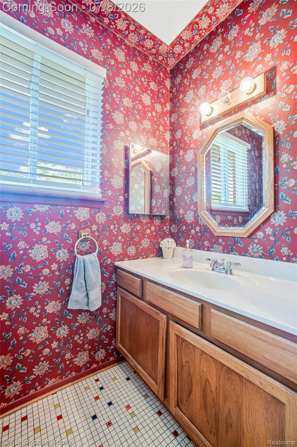 16720 Wayne Road Livonia, MI 48154 - Photo 16 of 29 Bathroom featuring floral wallpaper, a wood-finish vanity with a white countertop, an undermount sink, and a multi-color mosaic tile floor