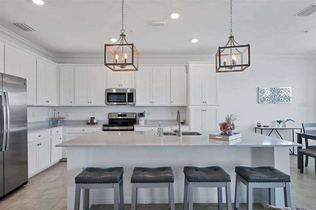 18114 Gawthrop Drive, Unit 405 Bradenton, FL 34211 - Photo 11 of 72 a kitchen with stainless steel appliances a dining table chairs and cabinets