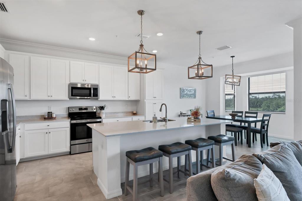 18114 Gawthrop Drive, Unit 405 Bradenton, FL 34211 - Photo 12 of 72 a kitchen with stainless steel appliances granite countertop a stove a sink a dining table and chairs with wooden floor