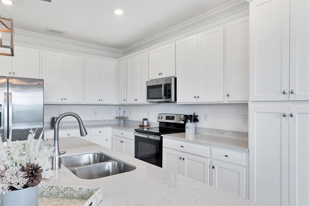 18114 Gawthrop Drive, Unit 405 Bradenton, FL 34211 - Photo 13 of 72 a kitchen with white cabinets sink and stainless steel appliances