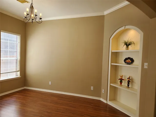 an empty room with wooden floor closet and windows