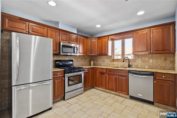 a kitchen with granite countertop cabinets stainless steel appliances and a window