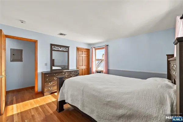 a spacious bedroom with a bed and wooden floor