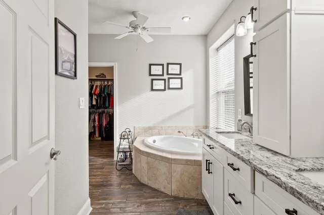 a spacious bathroom with a tub sink and mirror