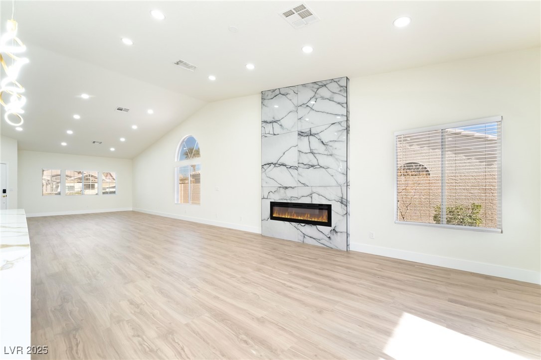 9205 Desert Village Avenue Las Vegas, NV 89147 - Photo 12 of 44 Unfurnished living room with recessed lighting, a premium fireplace, light wood finished floors, and vaulted ceiling