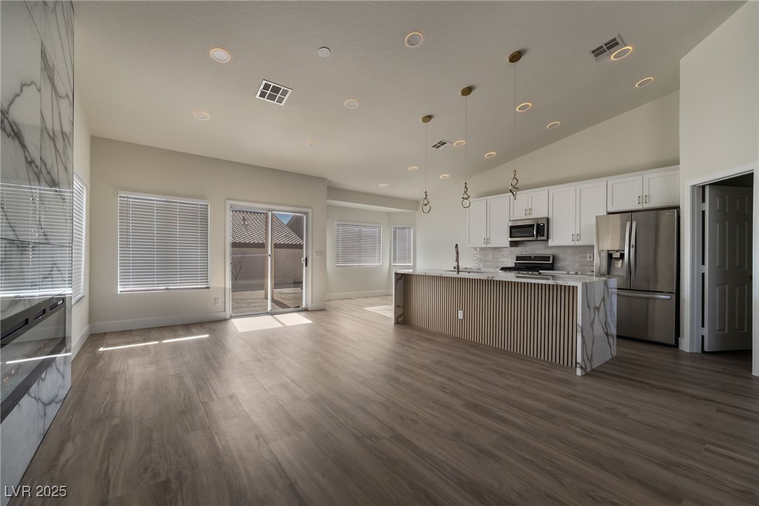 9205 Desert Village Avenue Las Vegas, NV 89147 - Photo 43 of 44 Kitchen with white cabinets, appliances with stainless steel finishes, open floor plan, an island with sink, and hanging light fixtures