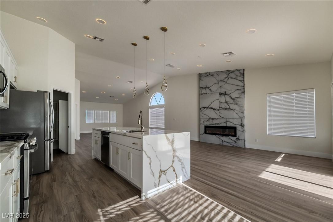 9205 Desert Village Avenue Las Vegas, NV 89147 - Photo 44 of 44 Kitchen featuring white cabinets, open floor plan, light stone counters, decorative light fixtures, and a center island with sink