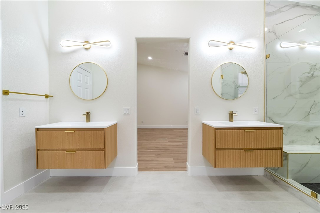 9205 Desert Village Avenue Las Vegas, NV 89147 - Photo 24 of 44 Full bathroom featuring two vanities, a marble finish shower, and light tile patterned floors