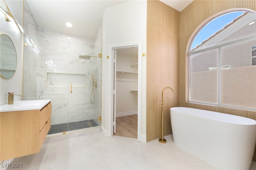 9205 Desert Village Avenue Las Vegas, NV 89147 - Photo 2 of 44 Full bathroom featuring vanity, a freestanding tub, a walk in closet, and a marble finish shower