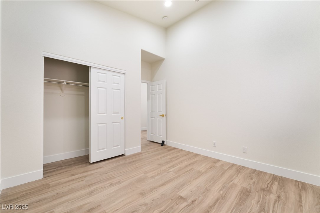 9205 Desert Village Avenue Las Vegas, NV 89147 - Photo 30 of 44 Unfurnished bedroom with light wood-style flooring, a towering ceiling, and a closet