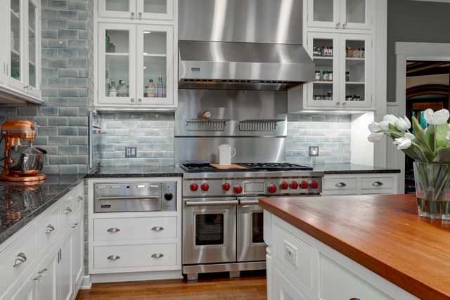 a kitchen with stainless steel appliances granite countertop a stove and a white cabinets