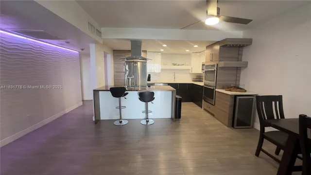 a kitchen with stainless steel appliances kitchen island granite countertop a table chairs in it and wooden floors