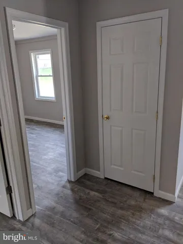a view of an empty room with wooden floor and a sink
