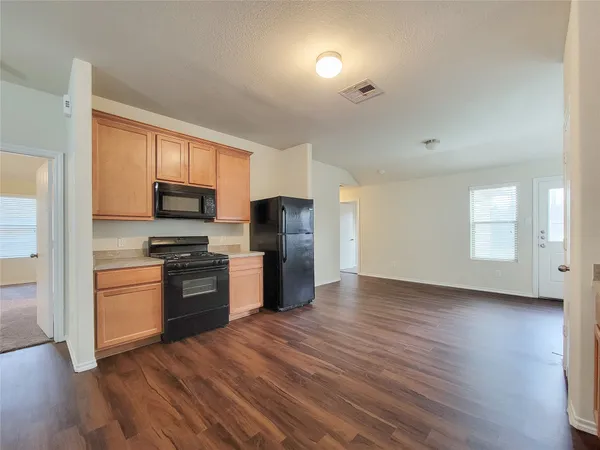 a kitchen with granite countertop a refrigerator and a stove top oven
