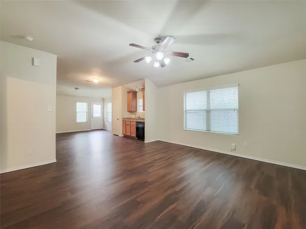 a view of an empty room with a kitchen and wooden floor
