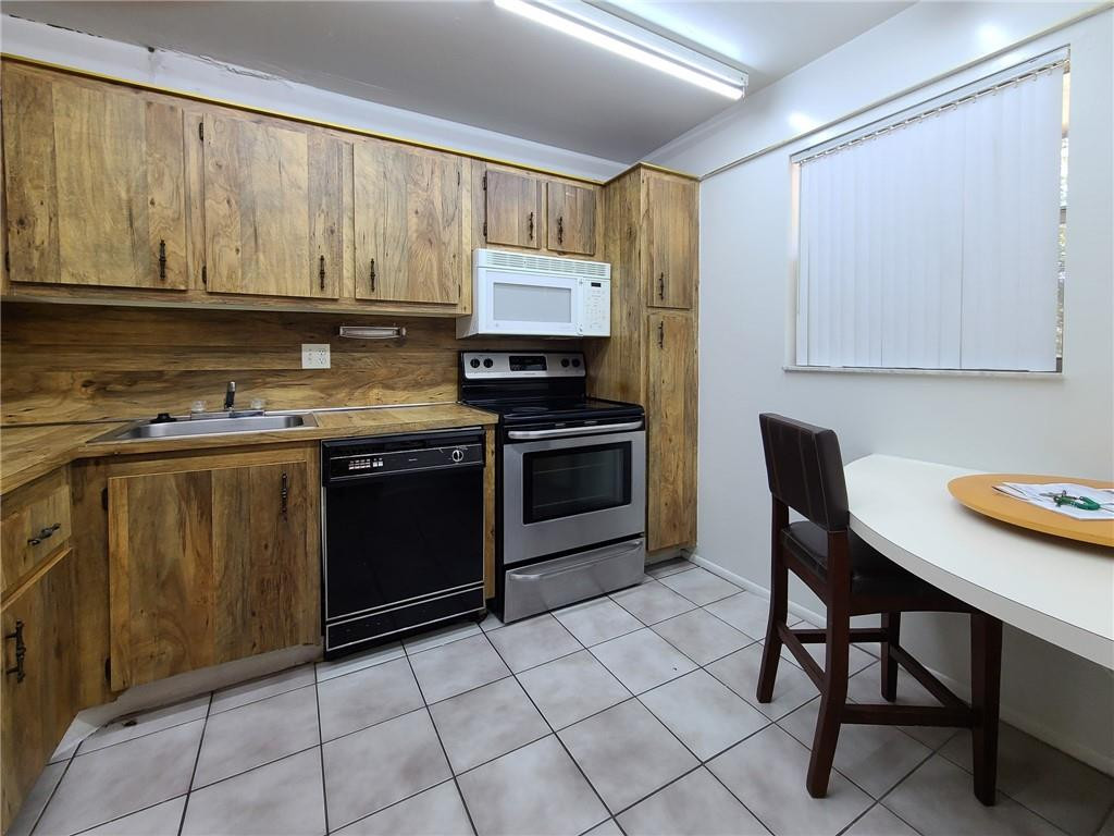 8301 Sands Point Boulevard, Unit 306S Tamarac, FL 33321 - Photo 1 of 13 a kitchen with a stove a sink and a microwave