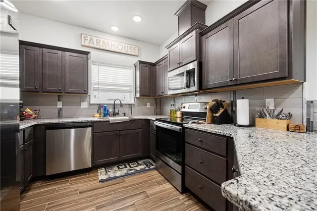 a kitchen with stainless steel appliances granite countertop a sink stove and cabinets
