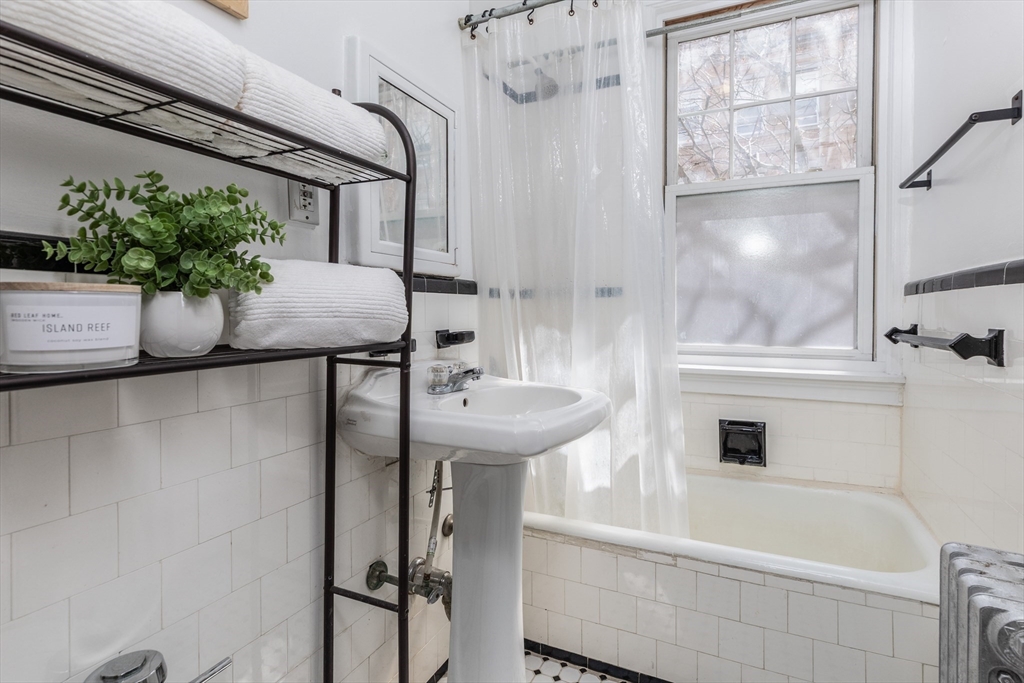 48 Strathmore Road, Unit 26 Boston, MA 02135 - Photo 13 of 15 a bathroom with a sink and mirror with bathtub