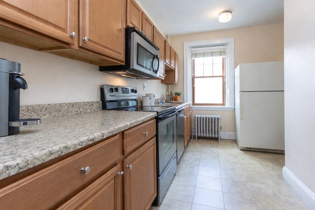 48 Strathmore Road, Unit 26 Boston, MA 02135 - Photo 9 of 15 a kitchen with stainless steel appliances granite countertop a sink a stove and a refrigerator