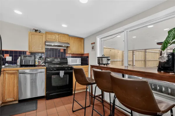 a kitchen with stainless steel appliances granite countertop a stove a sink a microwave a dining table and chairs