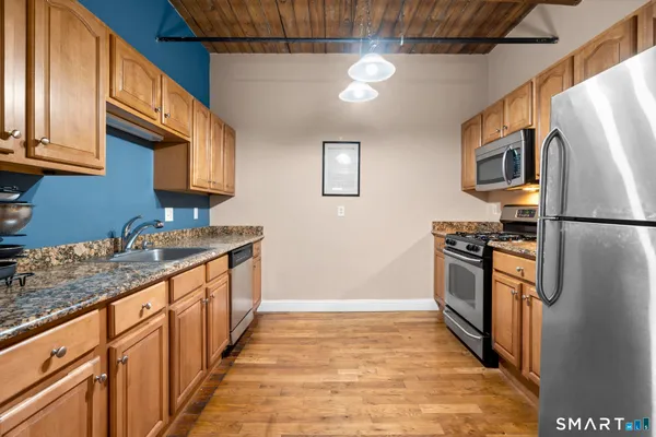 a kitchen with stainless steel appliances granite countertop a refrigerator a stove and a sink