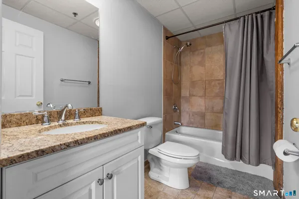 a bathroom with a granite countertop sink toilet and shower