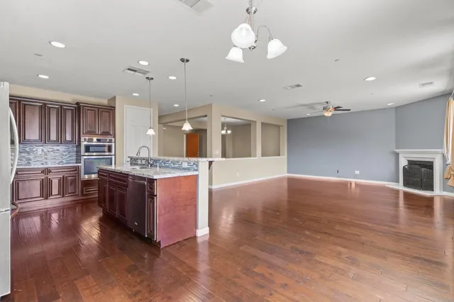 a large kitchen with stainless steel appliances granite countertop a large center island a stove a refrigerator cabinets and living room view