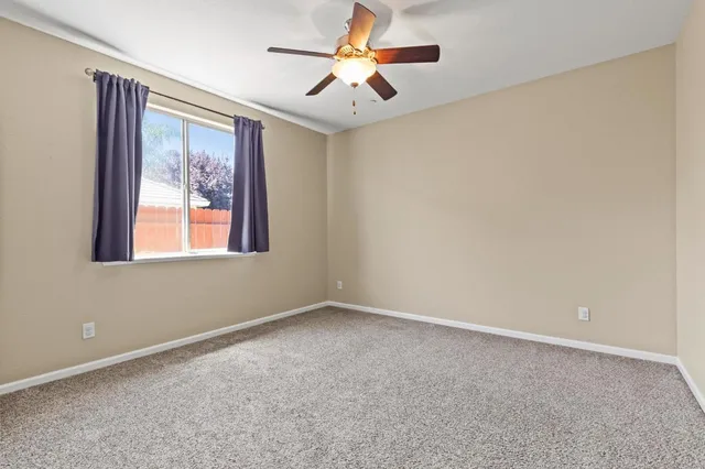 a view of an empty room with window and a ceiling fan