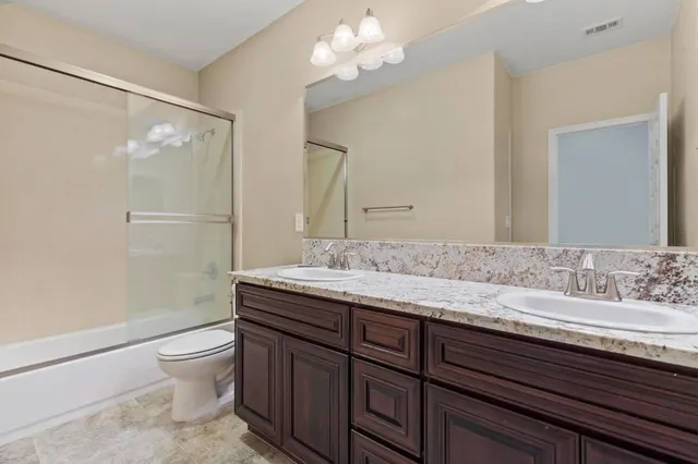 a bathroom with a granite countertop sink a toilet and a mirror
