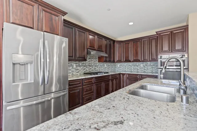 a kitchen with stainless steel appliances granite countertop a refrigerator sink and cabinets