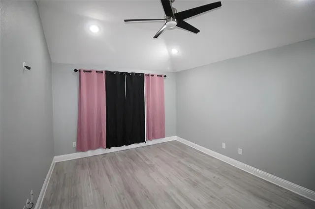 an empty room with wooden floor closet and windows