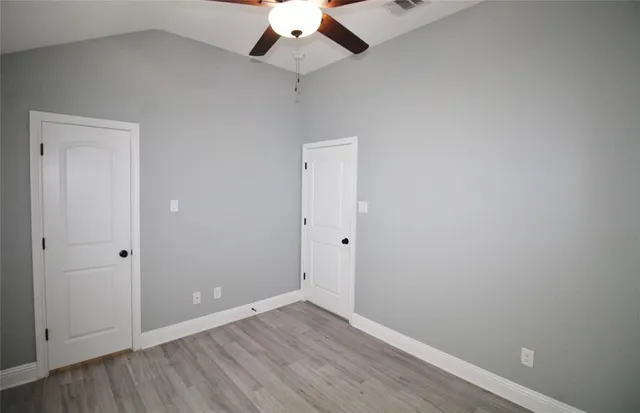 an empty room with a ceiling fan and wooden floor