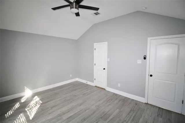 an empty room with wooden floor a ceiling fan and windows