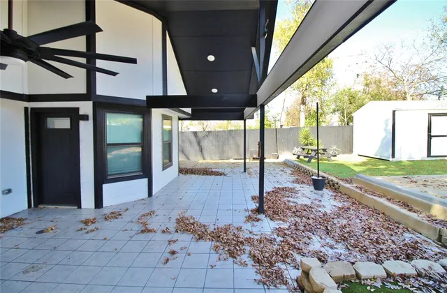 a view of a porch with a floor to ceiling window fire pit and wooden fence