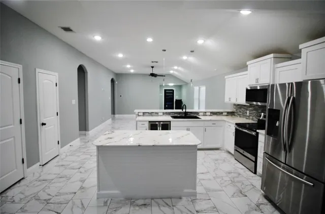 a large kitchen with kitchen island a sink stainless steel appliances and cabinets
