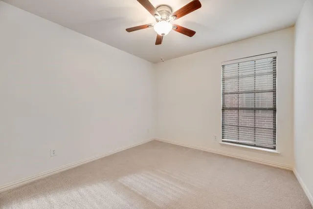 an empty room with chandelier fan and windows