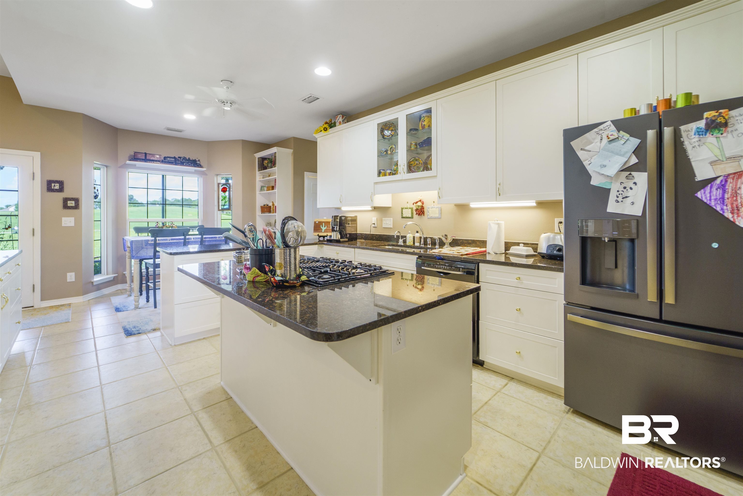 9505 Lakeview Drive Foley, AL 36535 - Photo 14 of 38 Kitchen featuring a kitchen island, stainless steel fridge with ice dispenser, white cabinets, glass insert cabinets, and light tile patterned floors