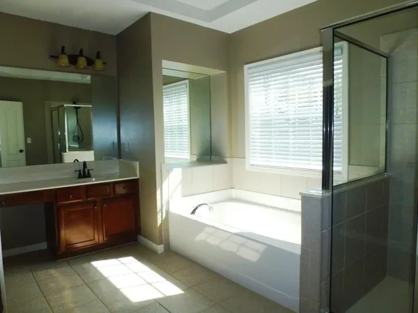 a spacious bathroom with a tub sink and mirror