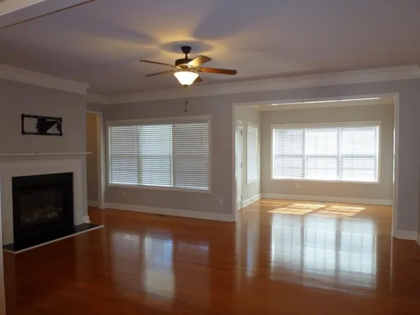 a view of an empty room with wooden floor and a window